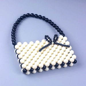 Handmade cream acrylic beaded handbag with black handle and decorative bow accent
