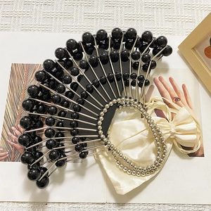 Detail of handcrafted fan-shaped clutch with black beads and silver chain handle