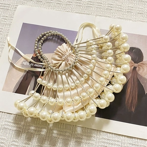 Detail of hand-woven pearl beaded fan bag with gold metal rods and satin drawstring pouch