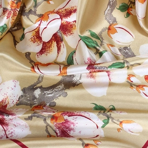 Vue macro du tissu en satin de soie avec imprimé de fleurs de magnolia en or champagne