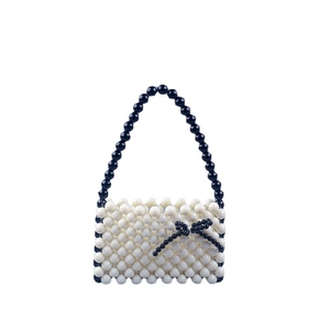 Handmade cream acrylic beaded handbag featuring a black bow and matching chain strap