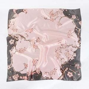 Close-up of pink cherry blossom print and satin texture on a large square floral scarf
