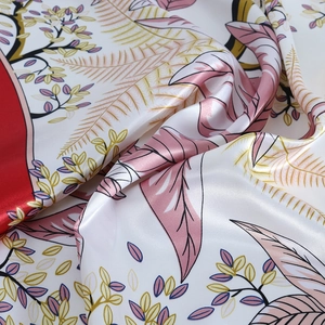 Gros plan d'un foulard en soie imprimé montrant des plis souples et des motifs de feuilles