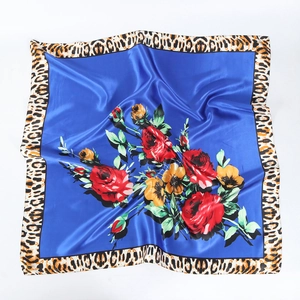 Detailed close-up of vibrant rose print on royal blue silk scarf with leopard border
