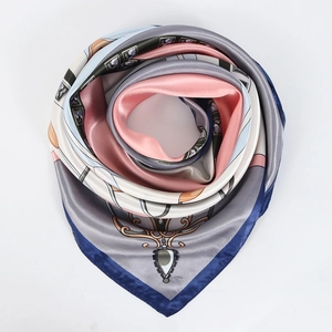 Détail d'un foulard en soie plié en rose montrant l'éclat satiné et le motif floral