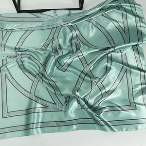 Detailed texture of mint green silk scarf with grey chain pattern and satin finish