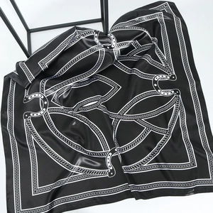 Detail shot of black and white silk scarf showing equestrian patterns and satin texture