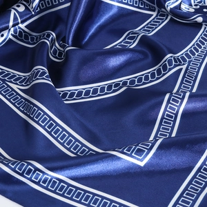 Close-up of smooth navy satin silk scarf featuring white nautical rope and geometric patterns