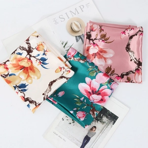 Detailed view of three 90cm silk scarves with floral magnolia patterns on white background