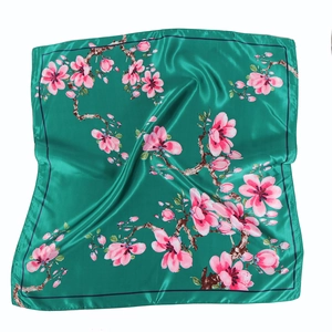 Detailed close-up of emerald green silk scarf with pink floral magnolia print pattern