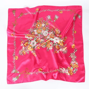 Détail d'un carré de soie fuchsia satiné avec motifs floraux et détails de glands dorés