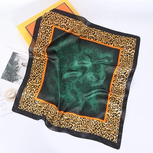 Detailed view of square silk scarf with floral print, leopard border and orange gift box