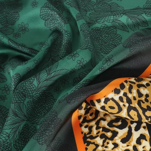 Detailed view of leopard print silk scarf with floral pattern and orange border