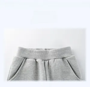 Dettaglio della vita elastica a coste e tasche laterali dei pantaloni sportivi grigio chiaro