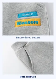 Dettaglio dei pantaloni in maglia grigia con ricamo di lettere e tasche laterali