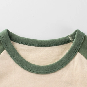 Détail d'un t-shirt raglan pour enfant avec manches contrastées olive et col rond côtelé