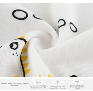 Close-up of soft white cotton fabric with dinosaur print and textile safety labels