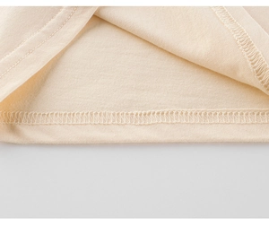 Gros plan détaillé des coutures surjetées sur un t-shirt en coton beige pour enfants