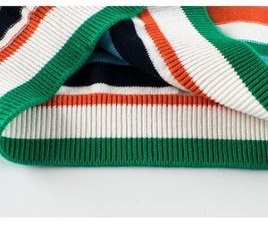 Detail of colorful striped knit sweater showing green ribbed hem and fabric texture