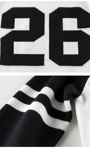 Close-up of black and white knit sweater showing number 26 jacquard and striped cuffs