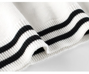 Detail of white knit sweater cuff with classic black stripes and ribbed texture finish