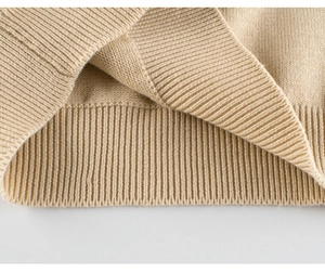 Close-up of beige knitted sweater showing ribbed cuffs and high-quality stitch detail