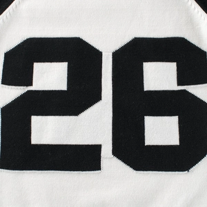 Close-up of knit sweater for children with black number 26 intarsia pattern on white fabric