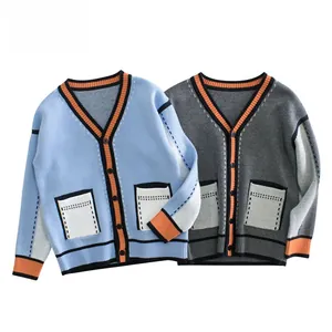 Detail of V-neck kids knit cardigan with orange trim and white pockets in blue and grey