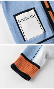 Detail of blue knit cardigan featuring cartoon style pocket and ribbed cuffs for kids