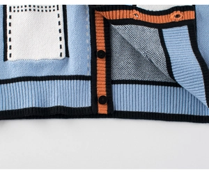 Detailed macro view of the sky blue knit cardigan with colorful patchwork and black buttons
