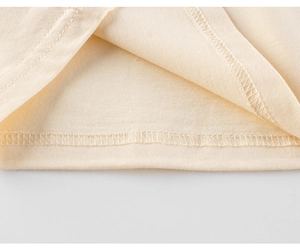 Detail of double-needle hem stitching on cream cotton dinosaur t-shirt for boys