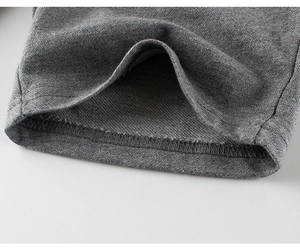 Détail macro du tissu en maille grise avec double couture sur l'ourlet du pantalon