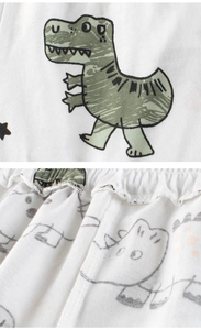 Detailed close-up of white cotton fabric with green dinosaur print and elastic waistband