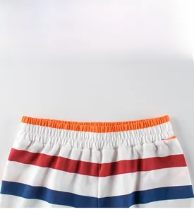 Detail of kids striped shorts featuring an orange elastic waistband and cotton fabric