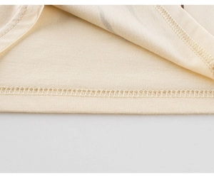 Close-up of the fine double-needle stitching on the hem of a soft beige cotton vest