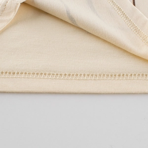 Close-up of beige cotton knit toddler vest featuring reinforced hem and ribbed edging