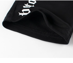 Détail de l'ourlet à double couture et de l'imprimé gothique blanc sur short en coton noir