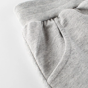 Close-up of light grey cotton knit kids' shorts with elastic ribbed waistband and side pockets