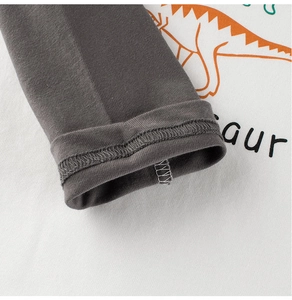 Detail shot of grey cuff stitching and cotton fabric with cartoon dinosaur print