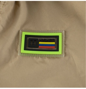 Detailed macro view of the 3D embossed HIGHER PVC badge on this khaki boy's spring jacket