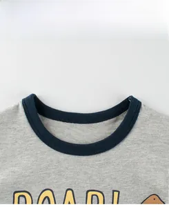 Détail de l'encolure côtelée bleu marine et du tissu gris sur le t-shirt dinosaure garçon