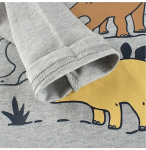 Détail du tissu en maille grise et de la couture sur le t-shirt dinosaure à manches longues