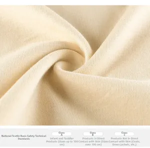 Close-up of soft beige cotton knit fabric texture with textile safety information labels