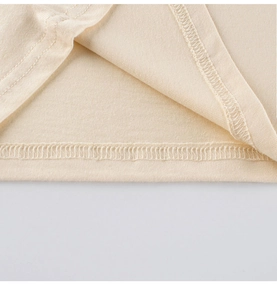 Macro detail of beige cotton knit fabric showing the double-needle stitched hem and texture
