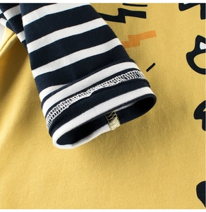 Détail d'un t-shirt jaune pour garçon avec poignets rayés bleus et coutures en coton fin