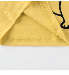 Détail de l'ourlet à double couture d'un t-shirt jaune pour garçon avec motif dinosaure