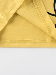 Gros plan de l'ourlet à double couture sur un t-shirt jaune en coton à manches longues