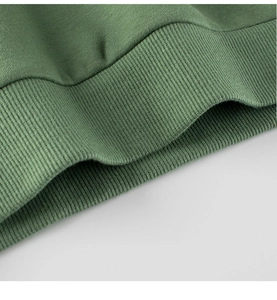 Détail du sweat vert pour enfant montrant la maille fine et la finition de l'ourlet