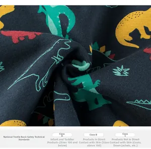 Detail of navy blue cotton knit fabric with dinosaur prints and textile safety standards