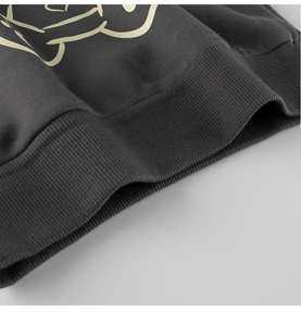 Detailed close-up of dark grey cotton hoodie ribbed hem and beige graphic print